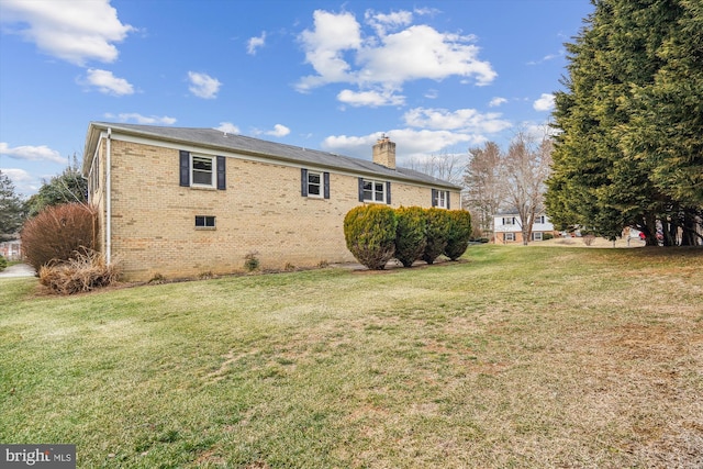 view of home's exterior with a yard, brick siding, and a chimney