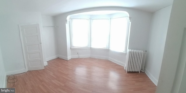 empty room featuring radiator heating unit and light hardwood / wood-style floors