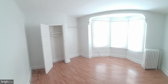 unfurnished bedroom featuring radiator heating unit and light hardwood / wood-style flooring