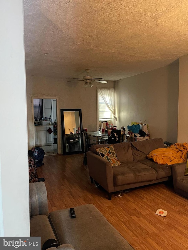 living room with ceiling fan, hardwood / wood-style floors, and a textured ceiling