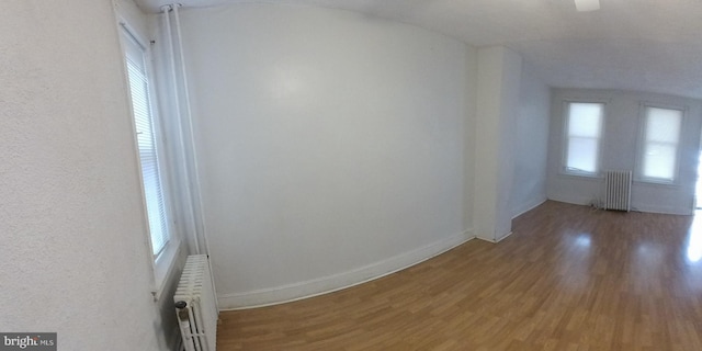 unfurnished room featuring radiator, a wealth of natural light, and wood-type flooring