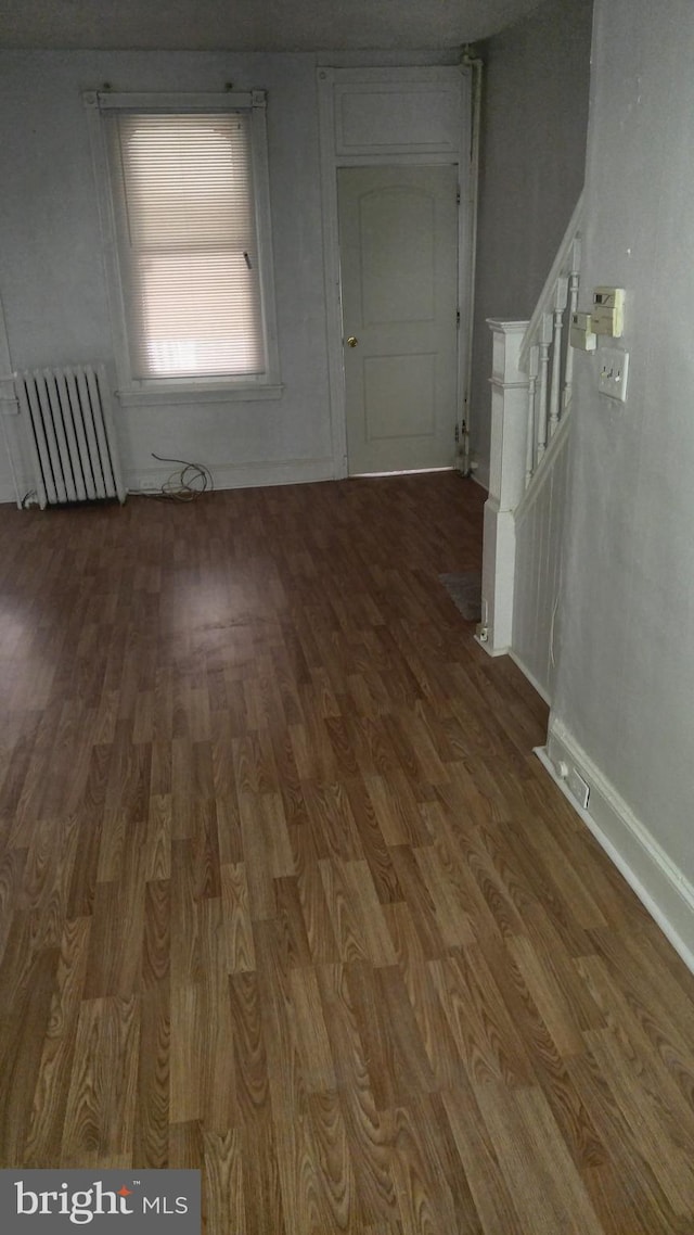 interior space with radiator heating unit and dark hardwood / wood-style flooring