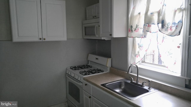 kitchen with white cabinetry, sink, and white appliances