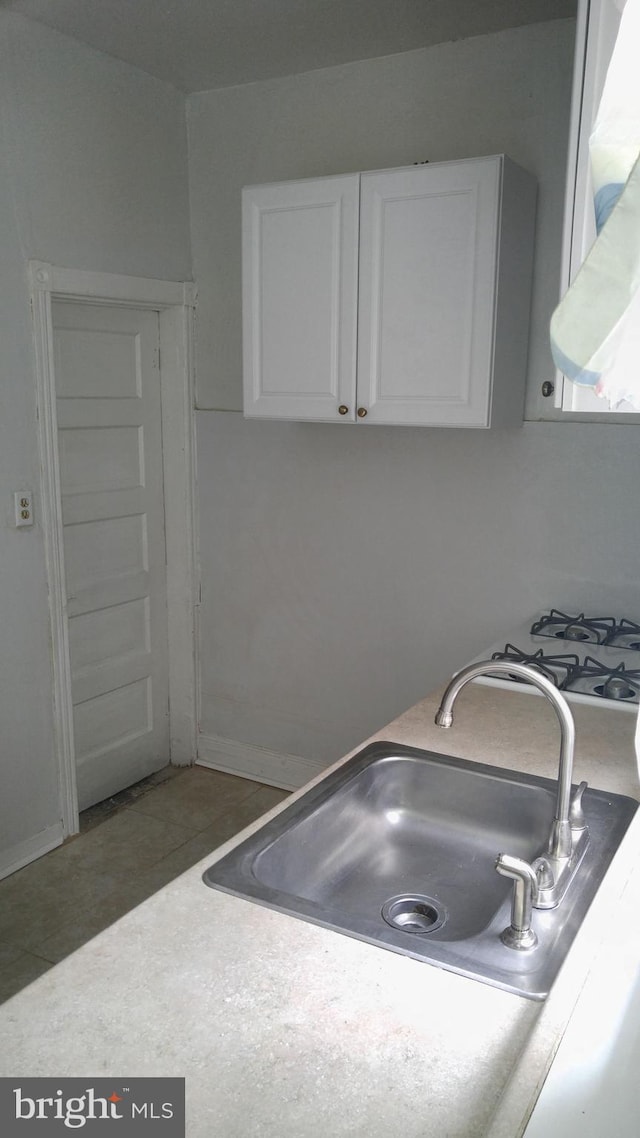 kitchen with white cabinetry, sink, exhaust hood, and dark tile patterned floors