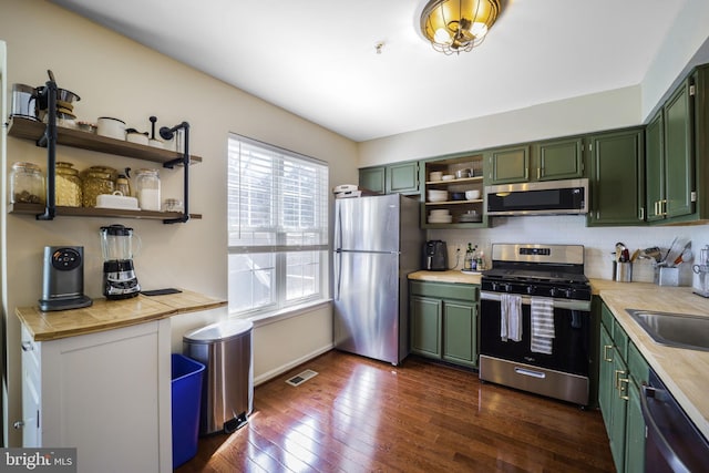 kitchen with visible vents, green cabinetry, light countertops, appliances with stainless steel finishes, and open shelves