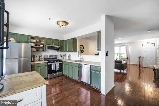 kitchen with open shelves, a sink, dark wood finished floors, stainless steel appliances, and green cabinetry