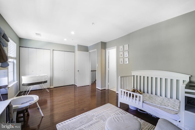 bedroom featuring wood finished floors, visible vents, baseboards, recessed lighting, and multiple closets