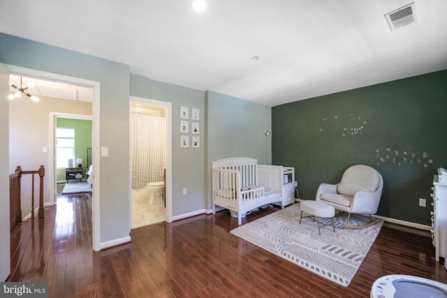 bedroom featuring hardwood / wood-style floors, a notable chandelier, baseboards, and visible vents