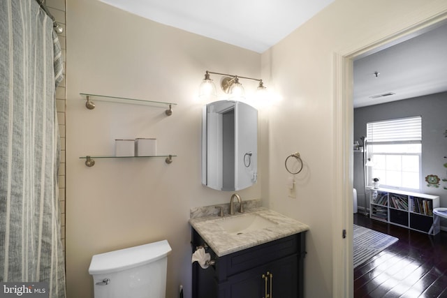 full bath with visible vents, toilet, vanity, and wood finished floors