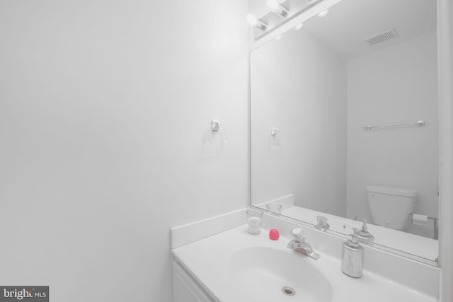 bathroom with vanity, toilet, and visible vents