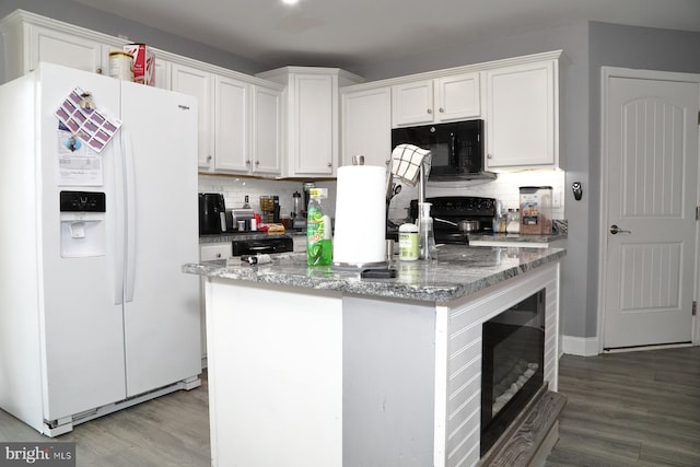 kitchen featuring white cabinetry, wood-type flooring, a center island, dark stone countertops, and white fridge with ice dispenser