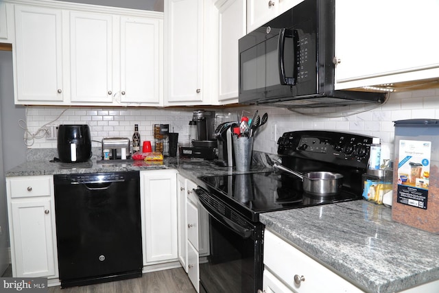 kitchen featuring light stone counters, white cabinets, decorative backsplash, and black appliances