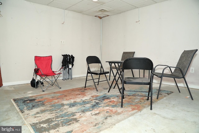 sitting room with concrete floors and a drop ceiling