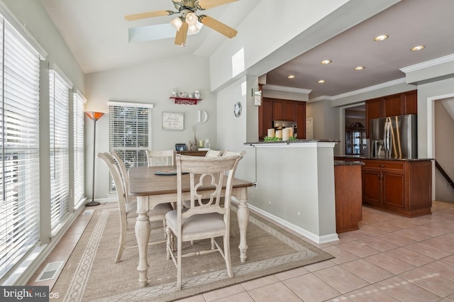 dining space with light tile patterned flooring, ceiling fan, ornamental molding, and vaulted ceiling