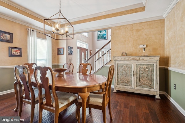 dining space featuring crown molding, dark hardwood / wood-style flooring, a raised ceiling, and a notable chandelier