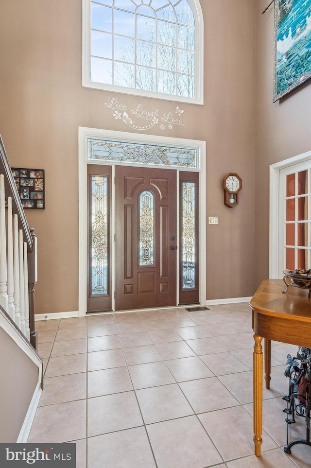 foyer entrance featuring light tile patterned floors, a healthy amount of sunlight, and a high ceiling