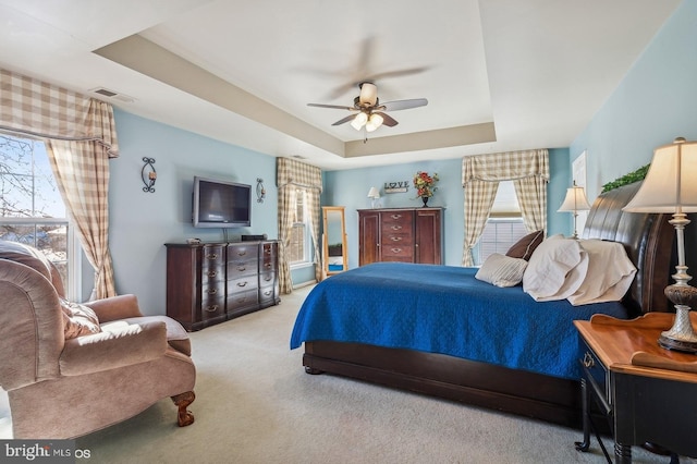 bedroom featuring light colored carpet, ceiling fan, and a tray ceiling