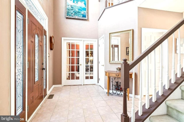 foyer entrance with french doors, a high ceiling, and light tile patterned floors