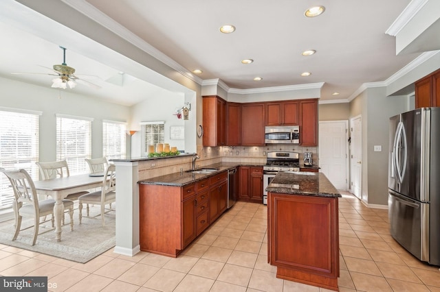 kitchen featuring sink, light tile patterned floors, dark stone countertops, stainless steel appliances, and kitchen peninsula