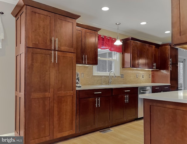 kitchen with sink, tasteful backsplash, hanging light fixtures, light hardwood / wood-style flooring, and dishwasher