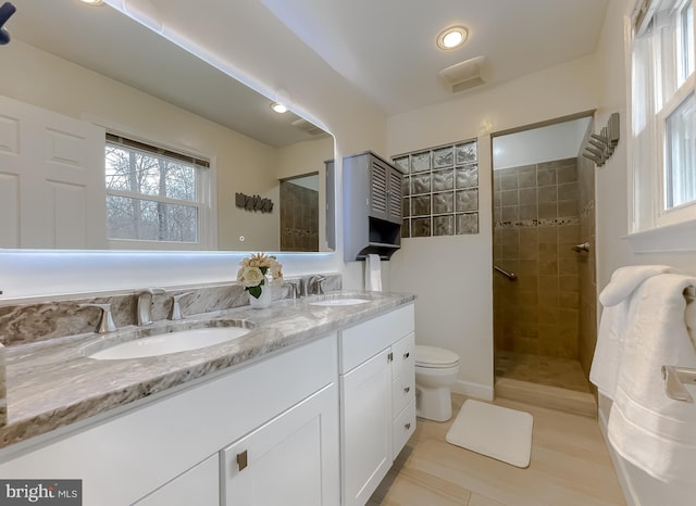 bathroom featuring vanity, tiled shower, and toilet