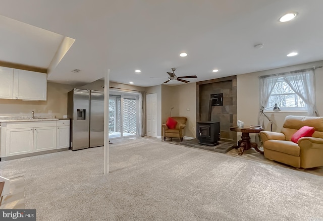 interior space with sink, ceiling fan, and a wood stove