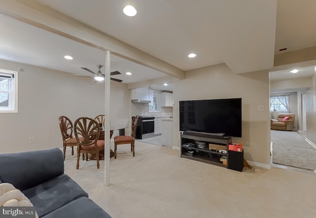 carpeted living room with ceiling fan and beam ceiling