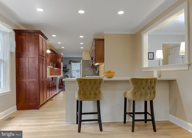 kitchen featuring ornamental molding, a breakfast bar area, and light hardwood / wood-style flooring