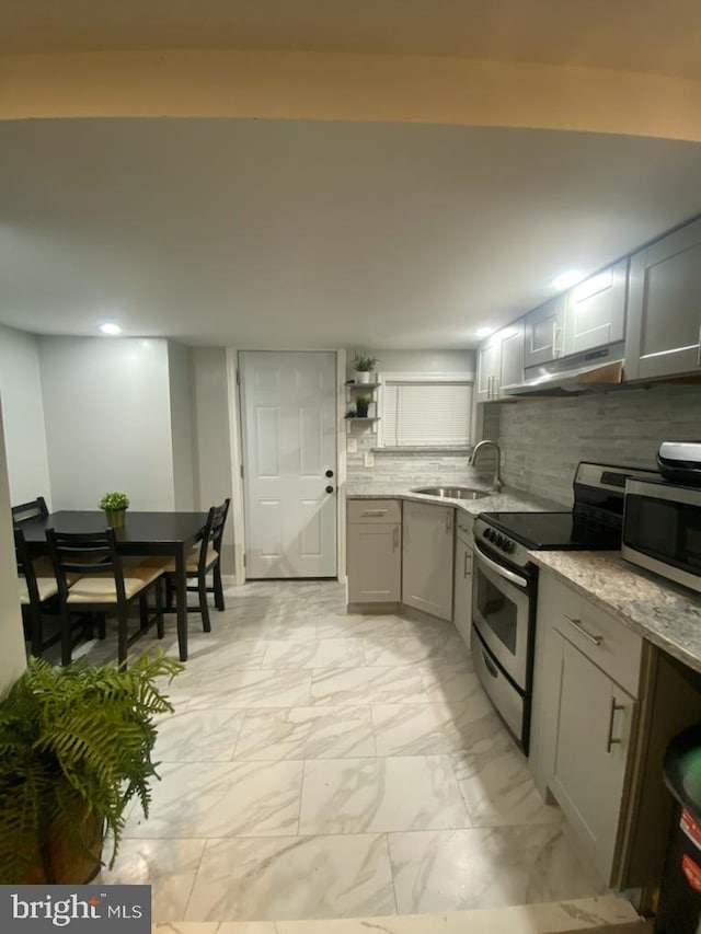 kitchen featuring sink, light stone counters, gray cabinets, stainless steel appliances, and backsplash