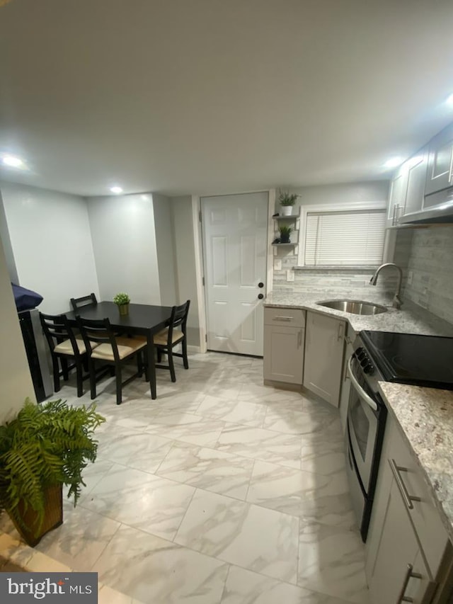 kitchen with sink, backsplash, light stone counters, and stainless steel range with electric stovetop