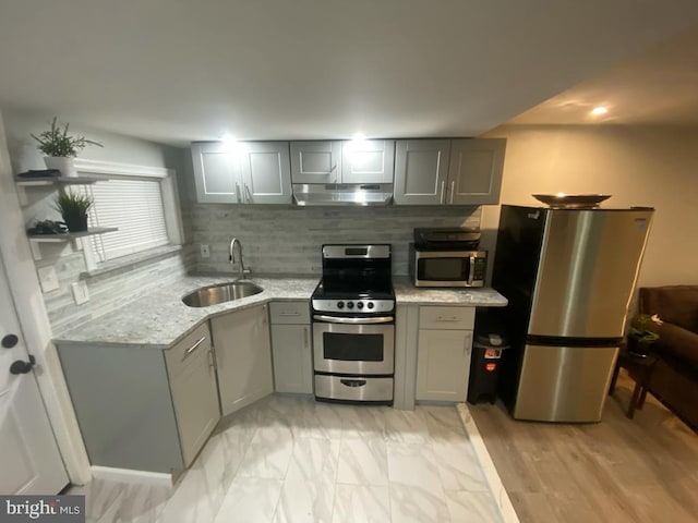 kitchen featuring appliances with stainless steel finishes, gray cabinets, sink, and decorative backsplash