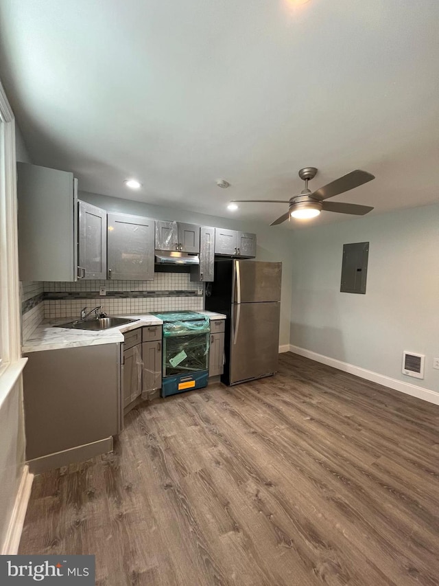 kitchen featuring appliances with stainless steel finishes, sink, backsplash, electric panel, and dark wood-type flooring