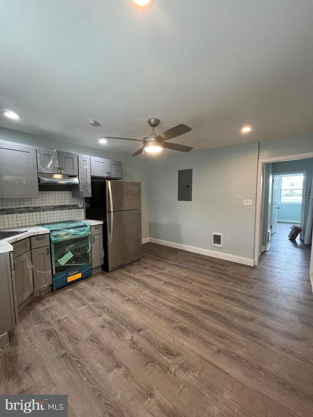 kitchen with range with electric stovetop, stainless steel fridge, electric panel, hardwood / wood-style flooring, and decorative backsplash