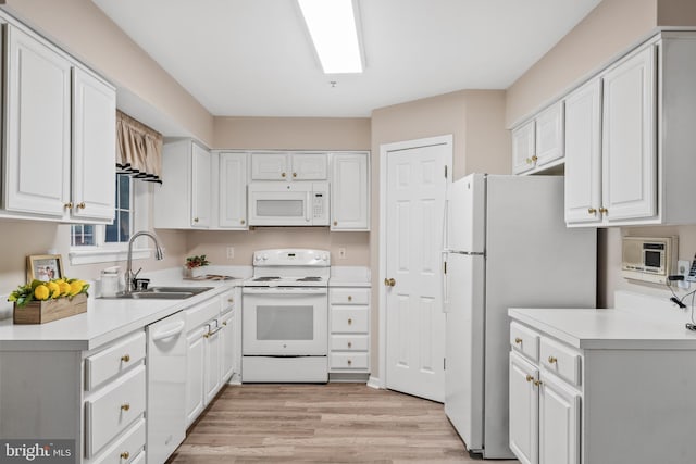 kitchen with sink, white cabinets, white appliances, and light hardwood / wood-style flooring