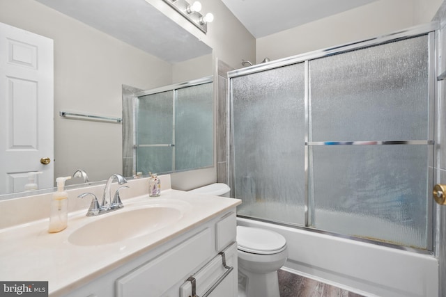 full bathroom featuring vanity, wood-type flooring, shower / bath combination with glass door, and toilet