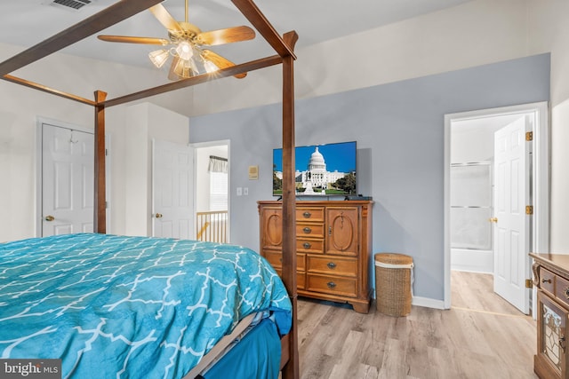 bedroom featuring ceiling fan, lofted ceiling, light hardwood / wood-style floors, and ensuite bath