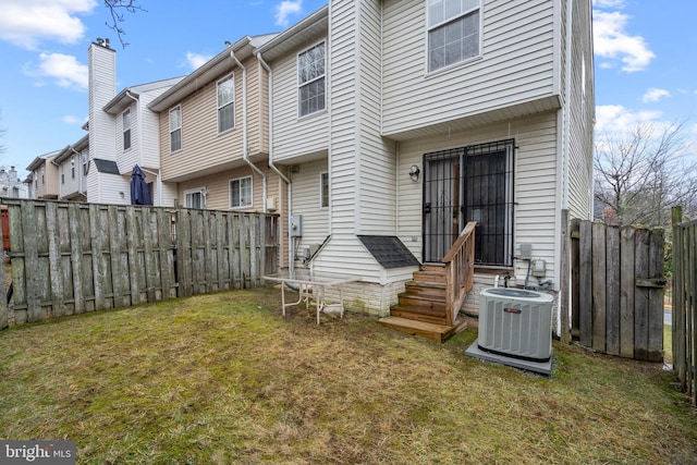 rear view of property featuring central AC and a yard