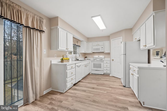 kitchen with white appliances, sink, light hardwood / wood-style flooring, and white cabinets