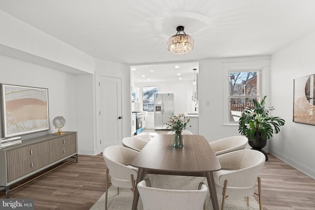 dining area featuring wood-type flooring, a chandelier, and sink