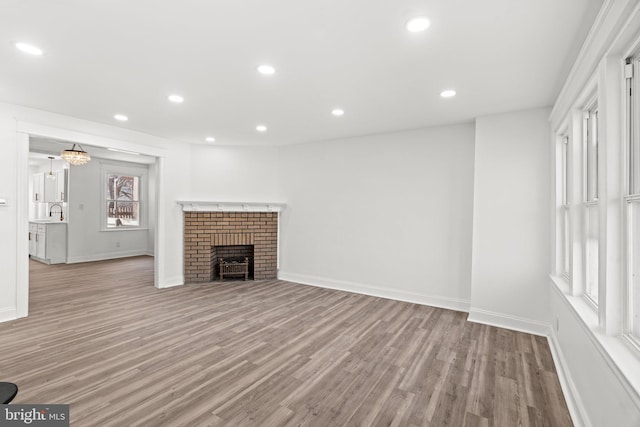 unfurnished living room featuring a brick fireplace and light hardwood / wood-style flooring