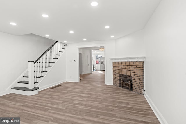 unfurnished living room with a brick fireplace and light hardwood / wood-style flooring