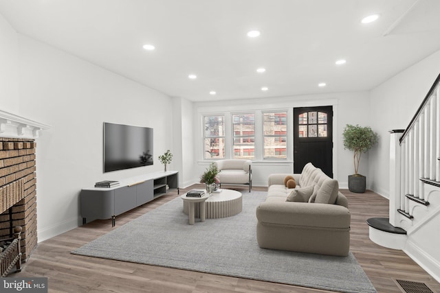 living room featuring a brick fireplace and hardwood / wood-style floors