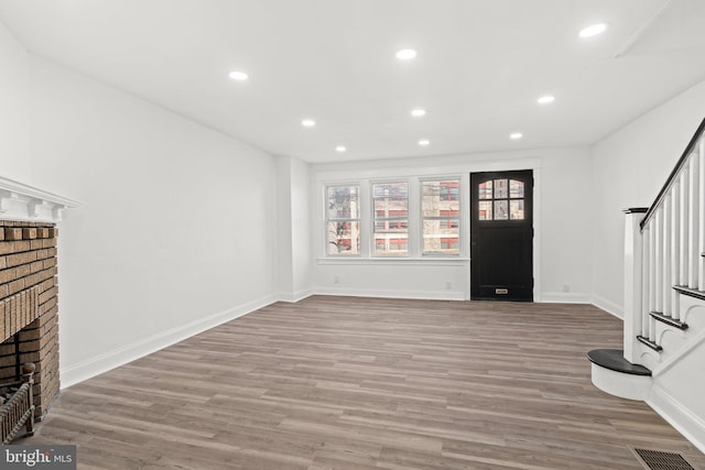 entryway with hardwood / wood-style flooring and a brick fireplace