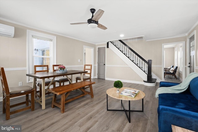 living room featuring a wall mounted air conditioner, crown molding, hardwood / wood-style floors, and ceiling fan