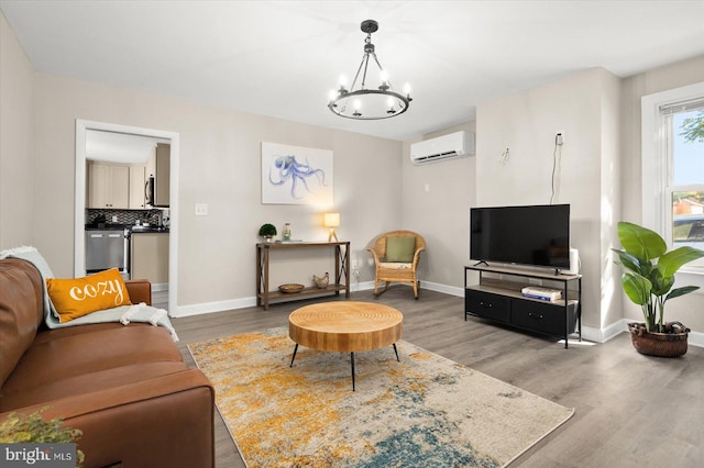 living room with a wall mounted AC, hardwood / wood-style floors, and a notable chandelier