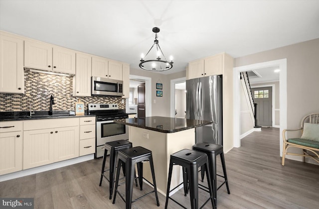 kitchen featuring a kitchen bar, sink, a center island, hanging light fixtures, and stainless steel appliances