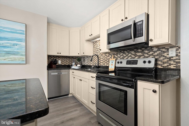 kitchen featuring sink, wood-type flooring, stainless steel appliances, decorative backsplash, and white cabinets