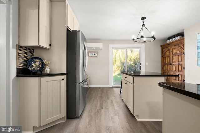 kitchen featuring stainless steel refrigerator, decorative light fixtures, tasteful backsplash, white cabinetry, and light hardwood / wood-style floors