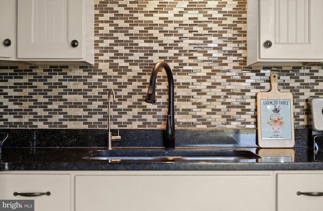 kitchen featuring tasteful backsplash, sink, dark stone countertops, and white cabinets