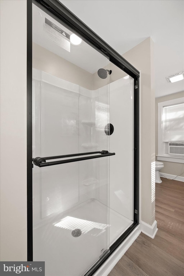 bathroom featuring hardwood / wood-style flooring, toilet, and a shower with door